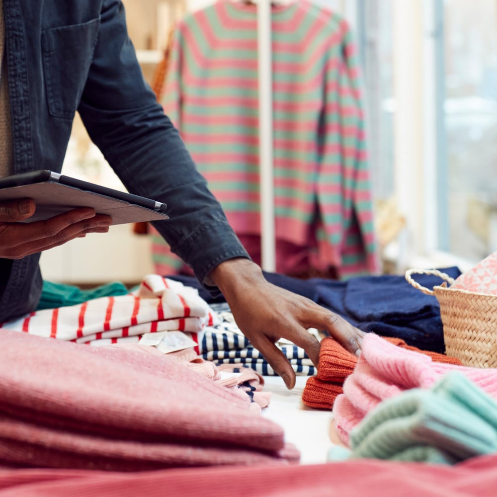 store manager checking digital tablet next to clothing display71