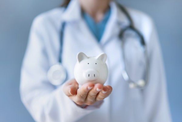 Doctor holding piggy bank to signify cost savings from healthcare supply chain automation